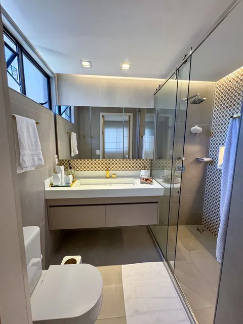 Banheiro com box de vidro e revestimento decorativo